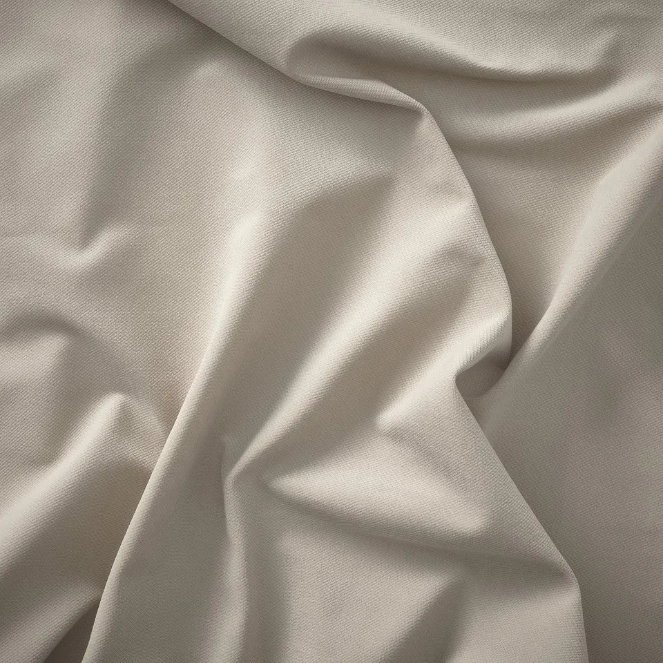 Close-up of soft, cream-colored fabric, showcasing smooth texture and delicate folds, highlighting its quality.