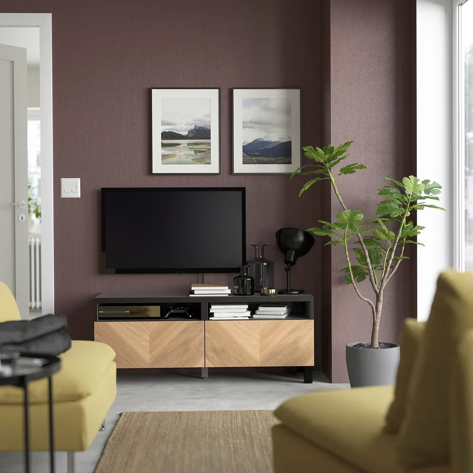 Modern living room with yellow chairs, wide tv stand, wall art, and green plant against purple walls.