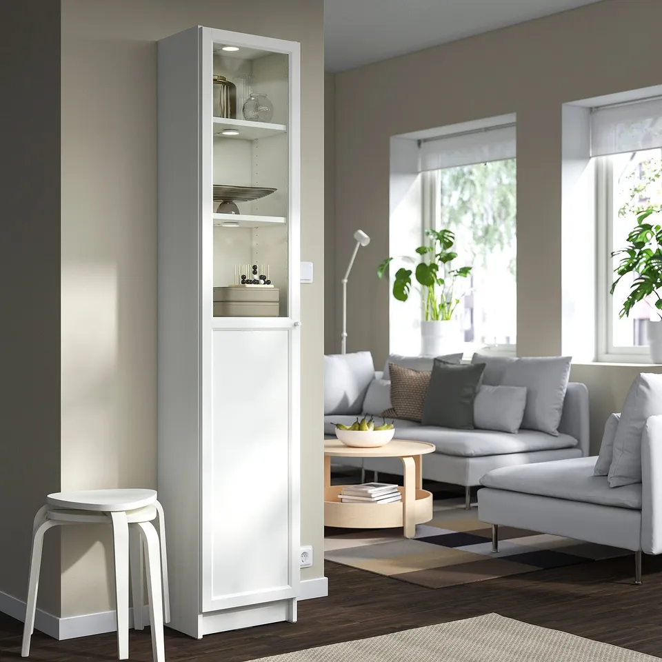 A BILLY bookcase in living room, tall glass doors, minimalist decor.