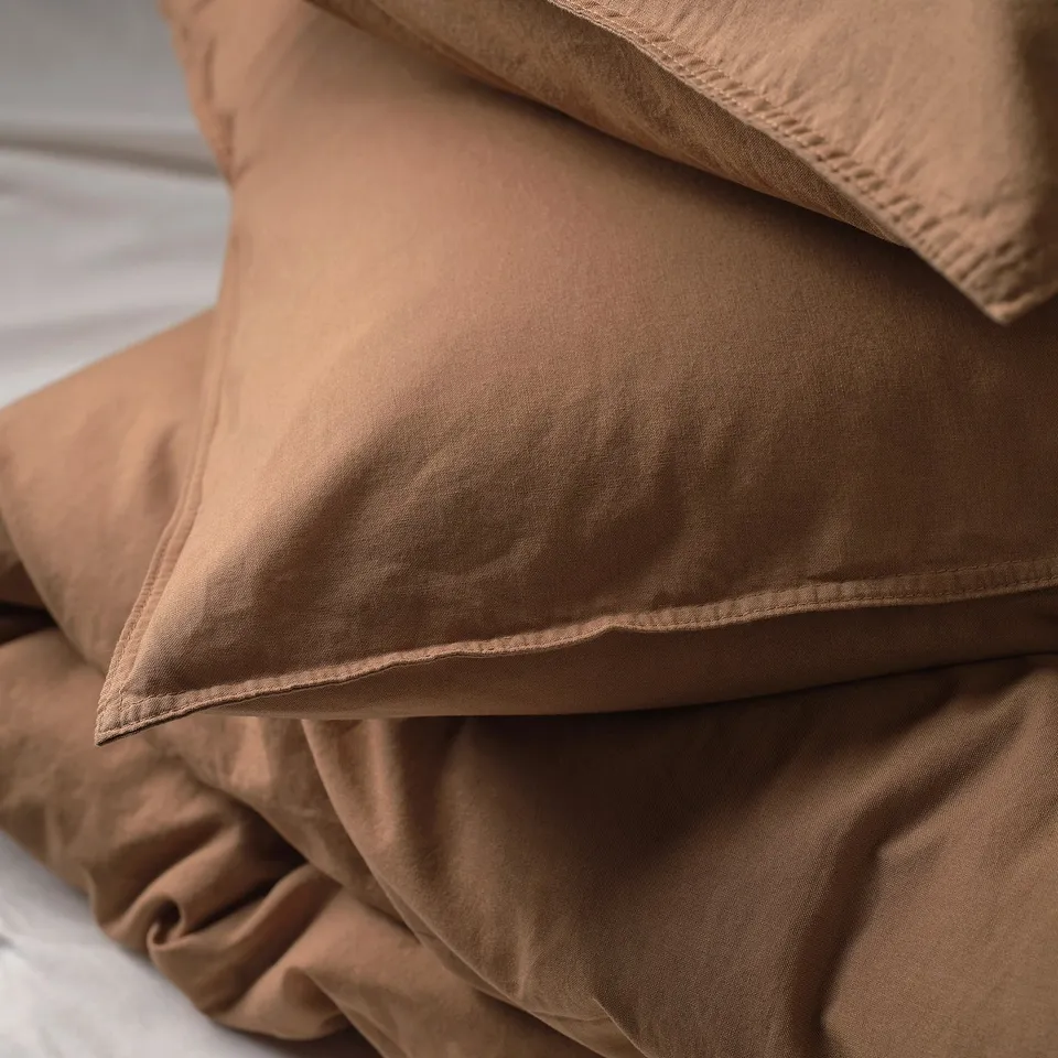 Soft, beige bed linens layered neatly. High-quality cotton, smooth and inviting texture, suggesting comfort and elegance.