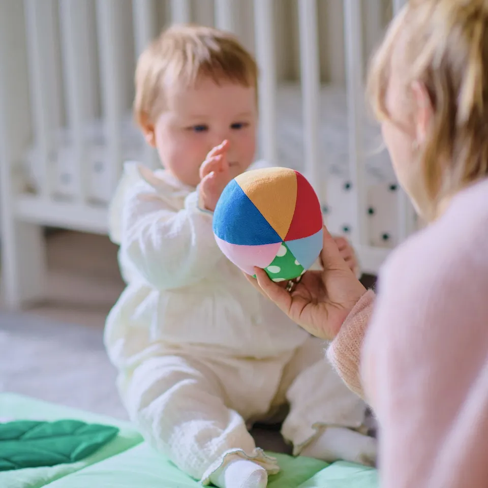 Baby playing with multicoloured jingly ball.