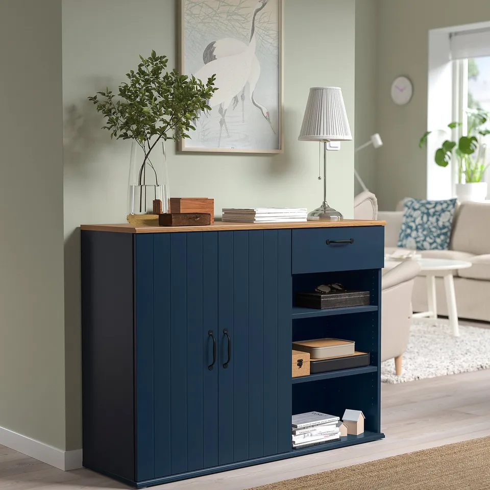 Modern living room with blue SKRUVBY sideboard, shelves, & storage. Under horse print, with lamp & plants.