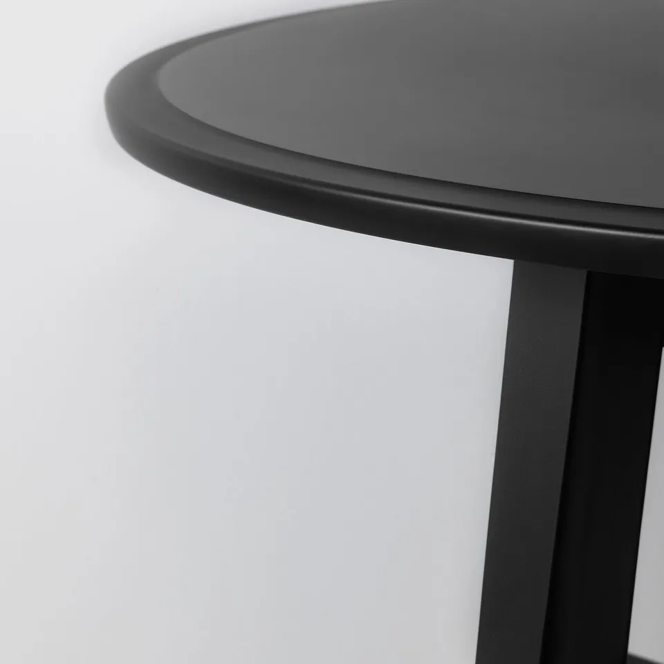 Close-up of sleek, curved edge of modern black table, showcasing smooth finish and sturdy design.