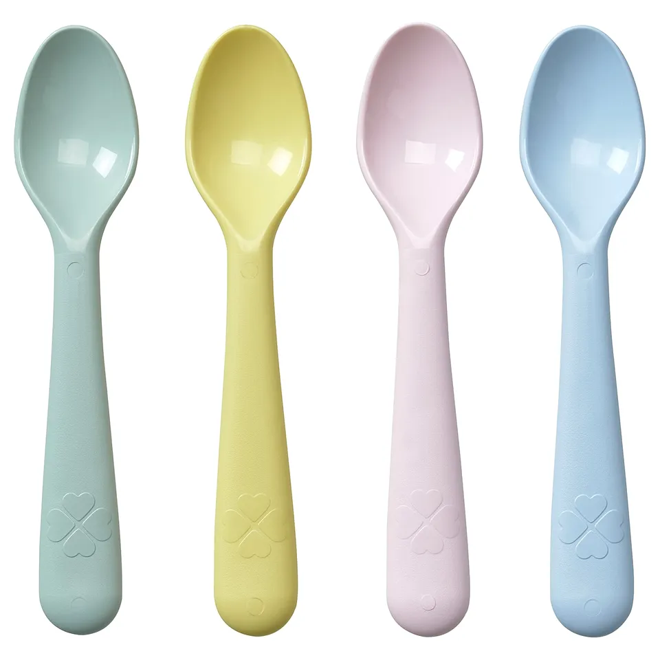 Four colourful spoons in turquoise, yellow, pink, and blue, made of polypropylene plastic with heart-shaped designs on handles.