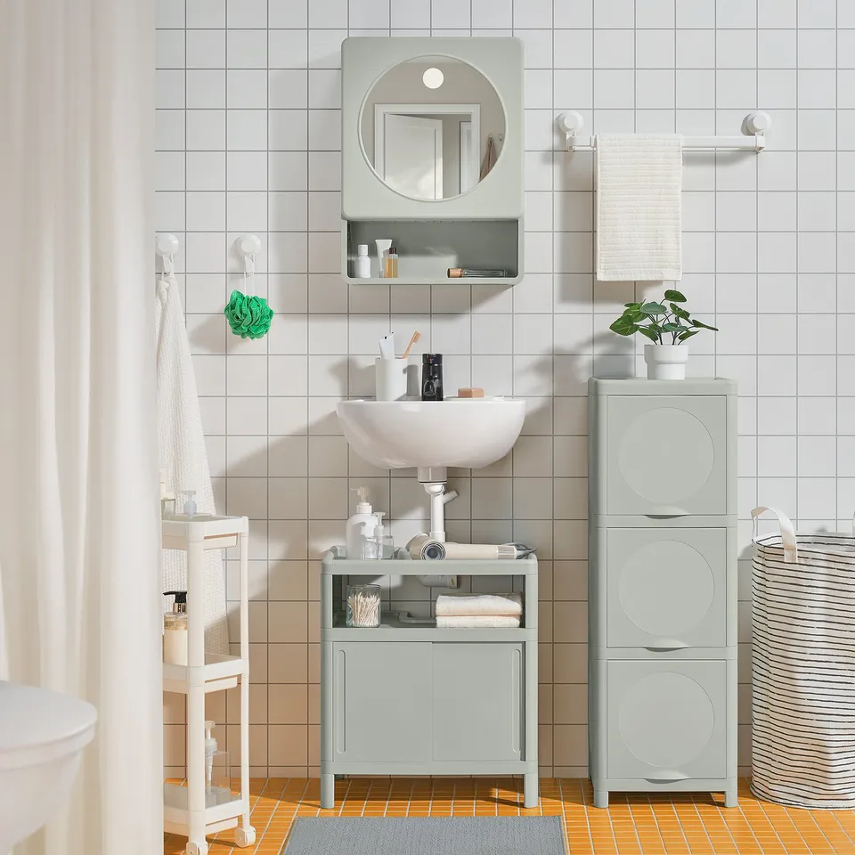 Grey bathroom vanity, white basin, grey cabinets, open shelves, orange tiles, hanging towels, plant.