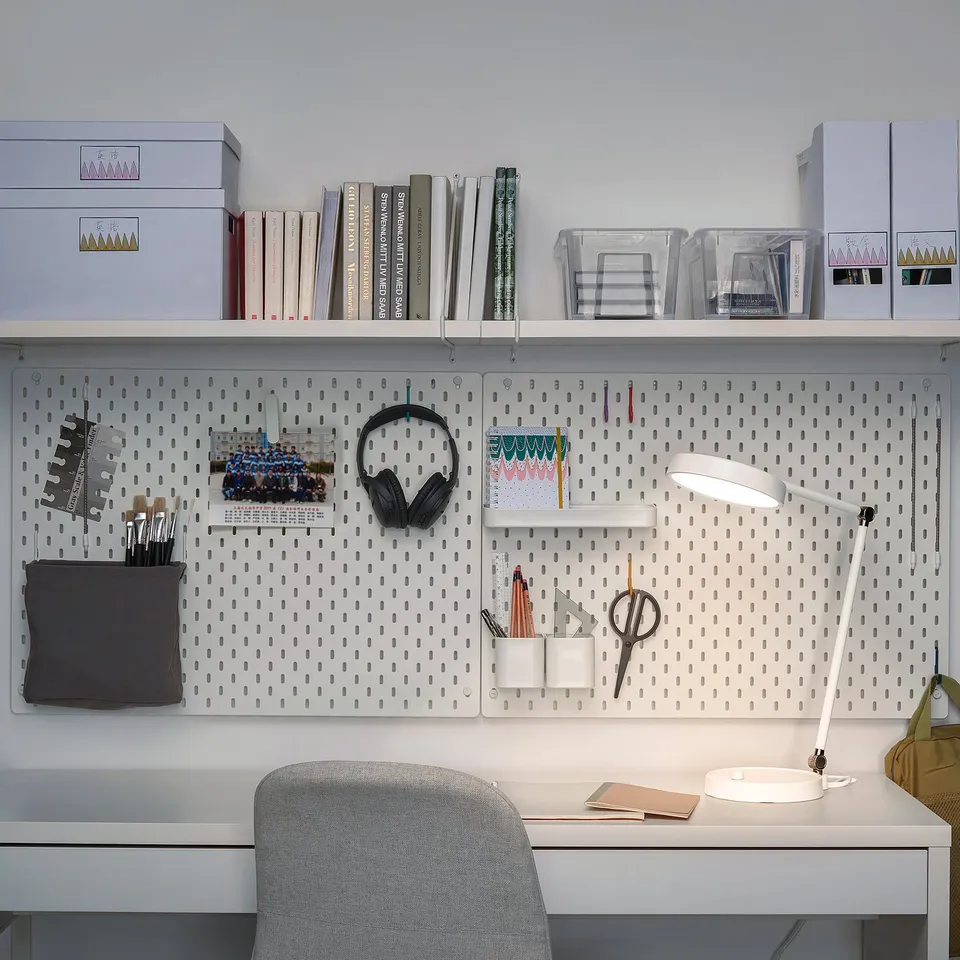 Home office setup with white ORSALA lamp, pegboard, books, and grey chair.