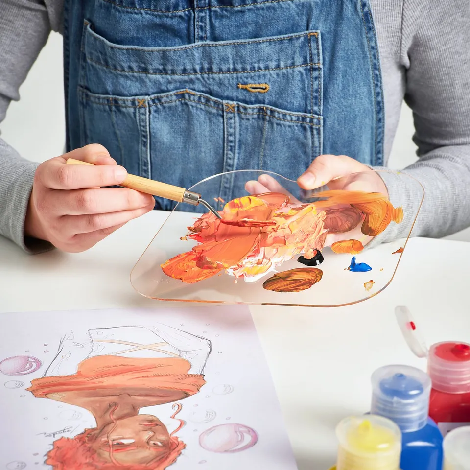 Mixing and applying paints on palette with spatula.