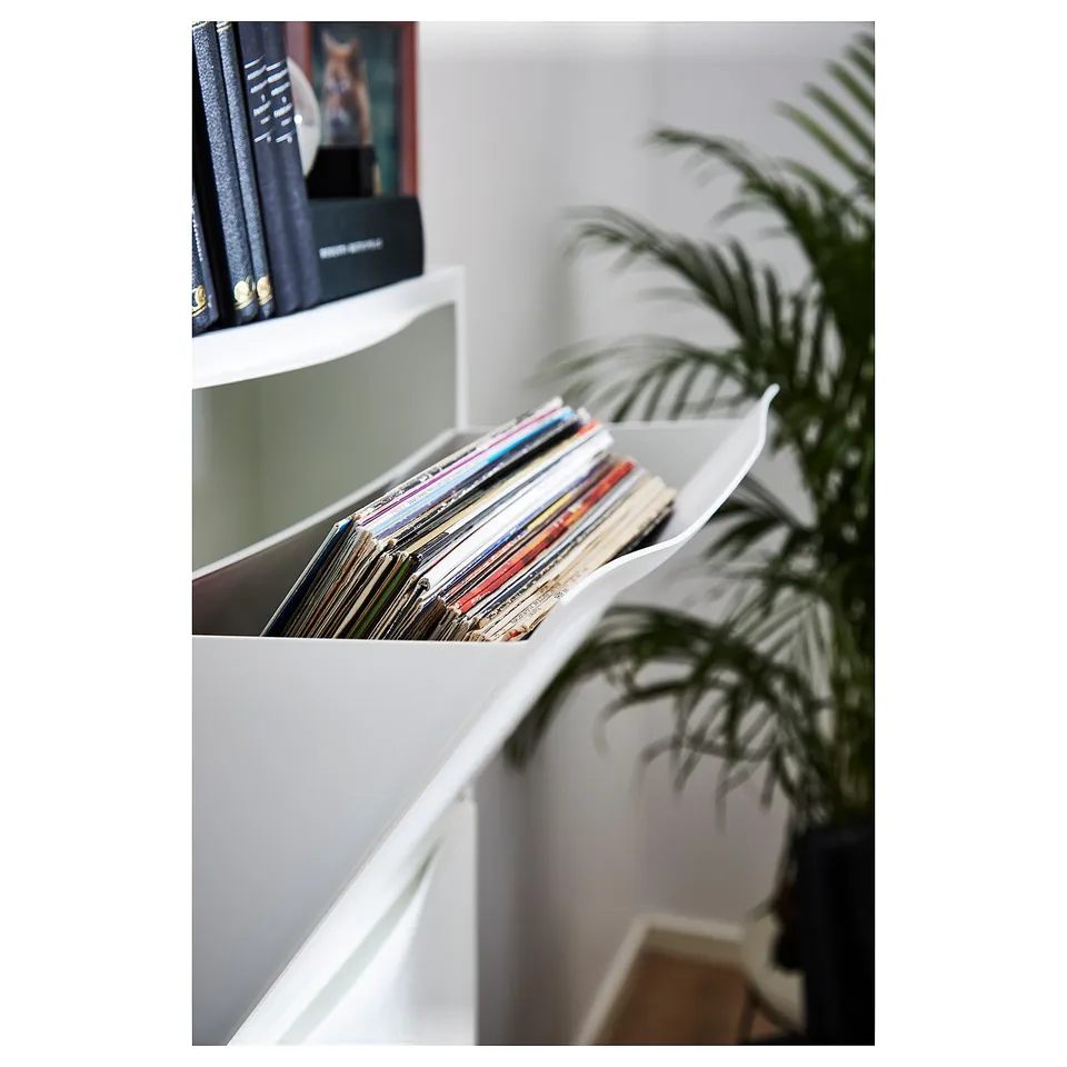 White TRONES storage cabinet holds records and books, with a green plant beside it.
