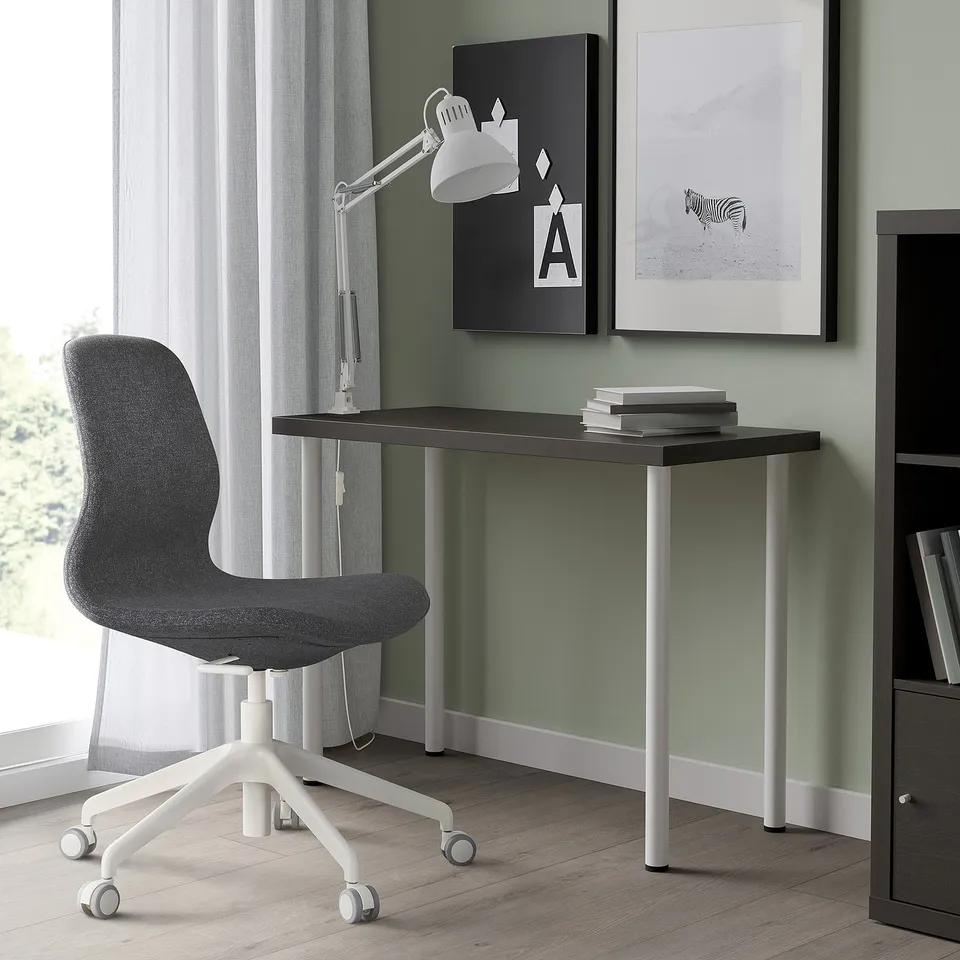 A modern home office with LINNMON desk, black top, silver legs, grey chair, books, and lamp. Compact yet functional.
