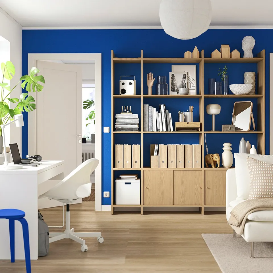 Home office with LÅDMAKARE bookshelf, blue wall, white desk, chair, pc, plant, open door.