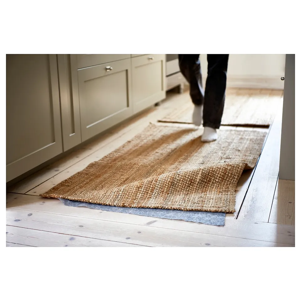 A beige rug with a person walking on it. The rug is placed on an underlay for better grip and floor protection.