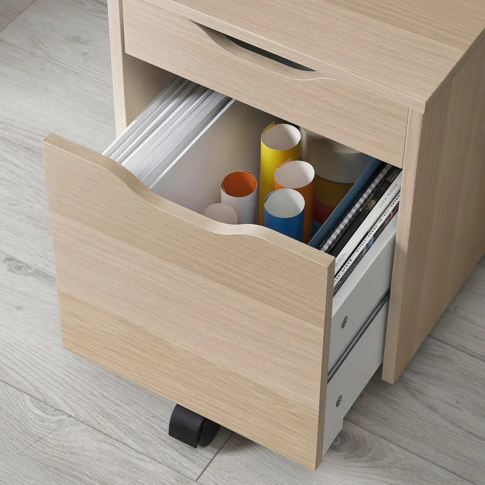A light wooden desk with an open drawer holding coloured cylindrical containers, likely ALEX series, offering organised storage.