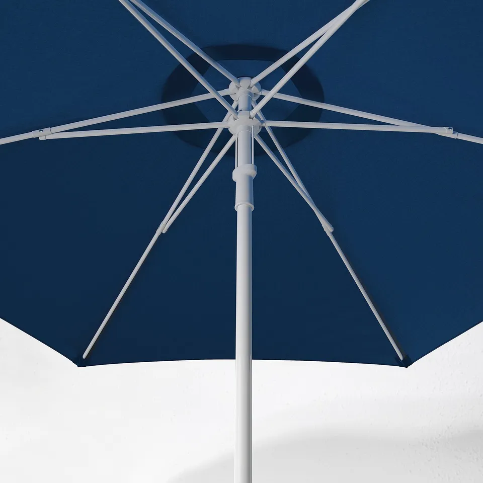 Blue patio parasol with white pole and ribs. Open and resting against white textured wall.