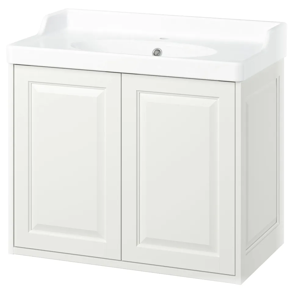 A white TÄNNFORSEN bathroom vanity with double doors, a raised backsplash, and a ceramic sink. It classic, elegant bevelled edges.