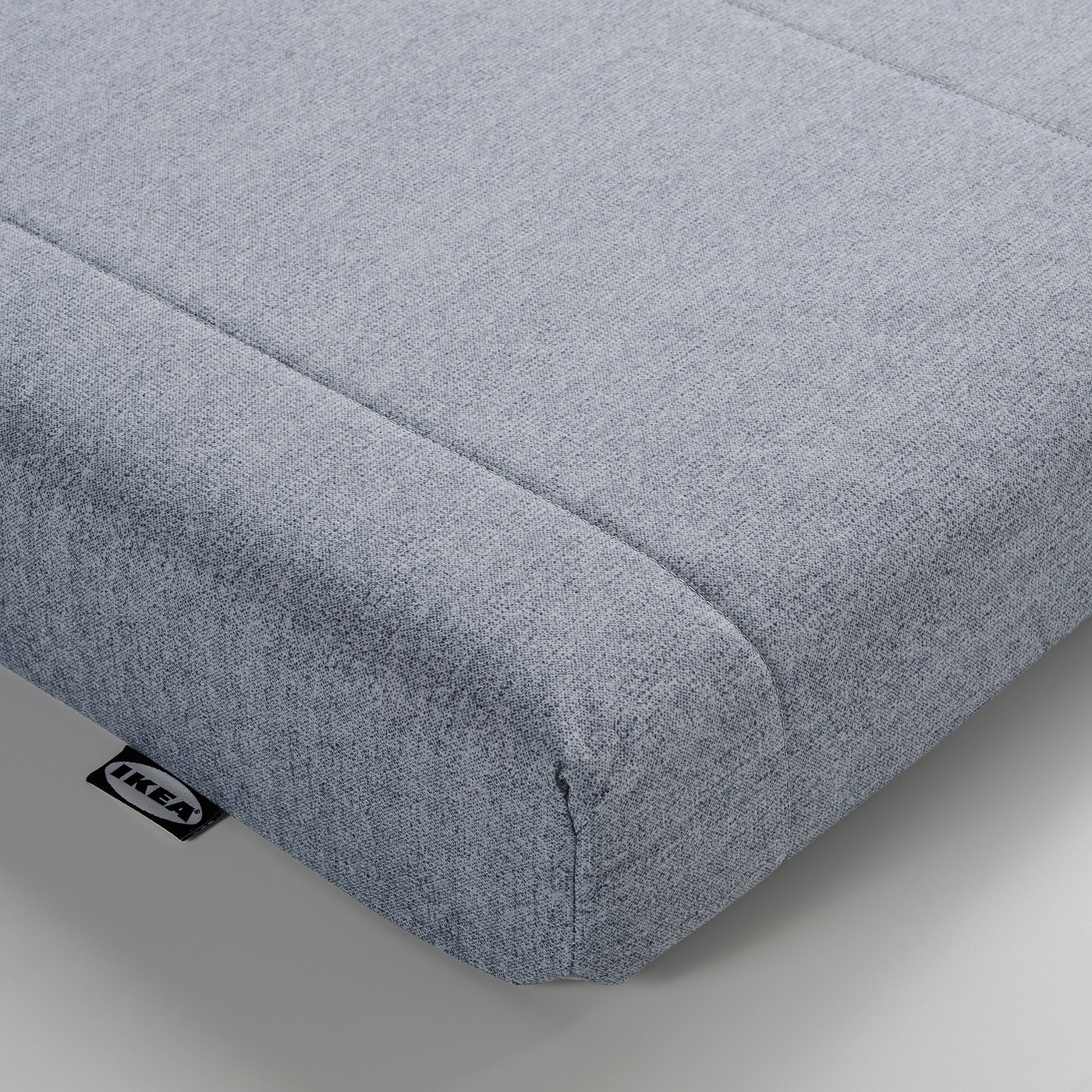Grey foam mattress, smooth texture, rectangular shape, ikea label, corner view.