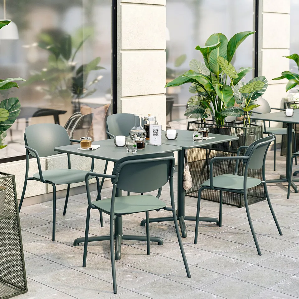 Modern outdoor dining set with grey VISINGSÖ tables and stackable chairs, cushioned seats and backs, surrounded by plants.