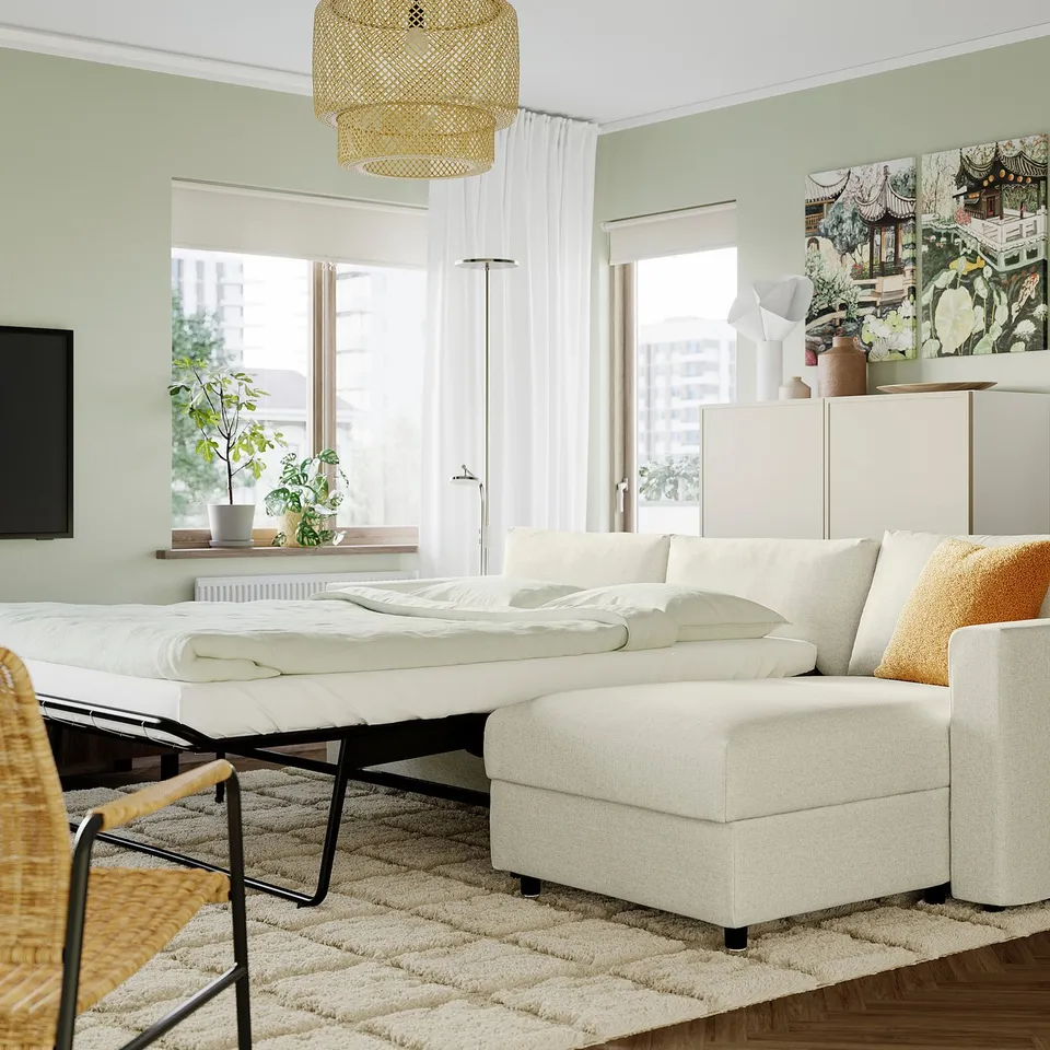 Modern living room with VIMLE white sofa-bed, large window, plants, and artwork. Sofa-bed is spacious and converts into a bed.