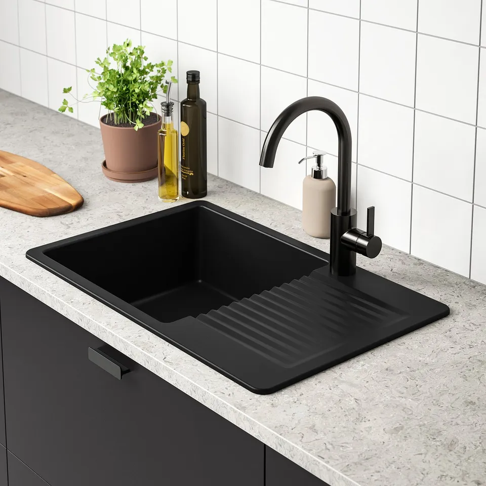 Black quartz sink with drainboard on grey countertop, matching black tap, plant, and oil bottles.