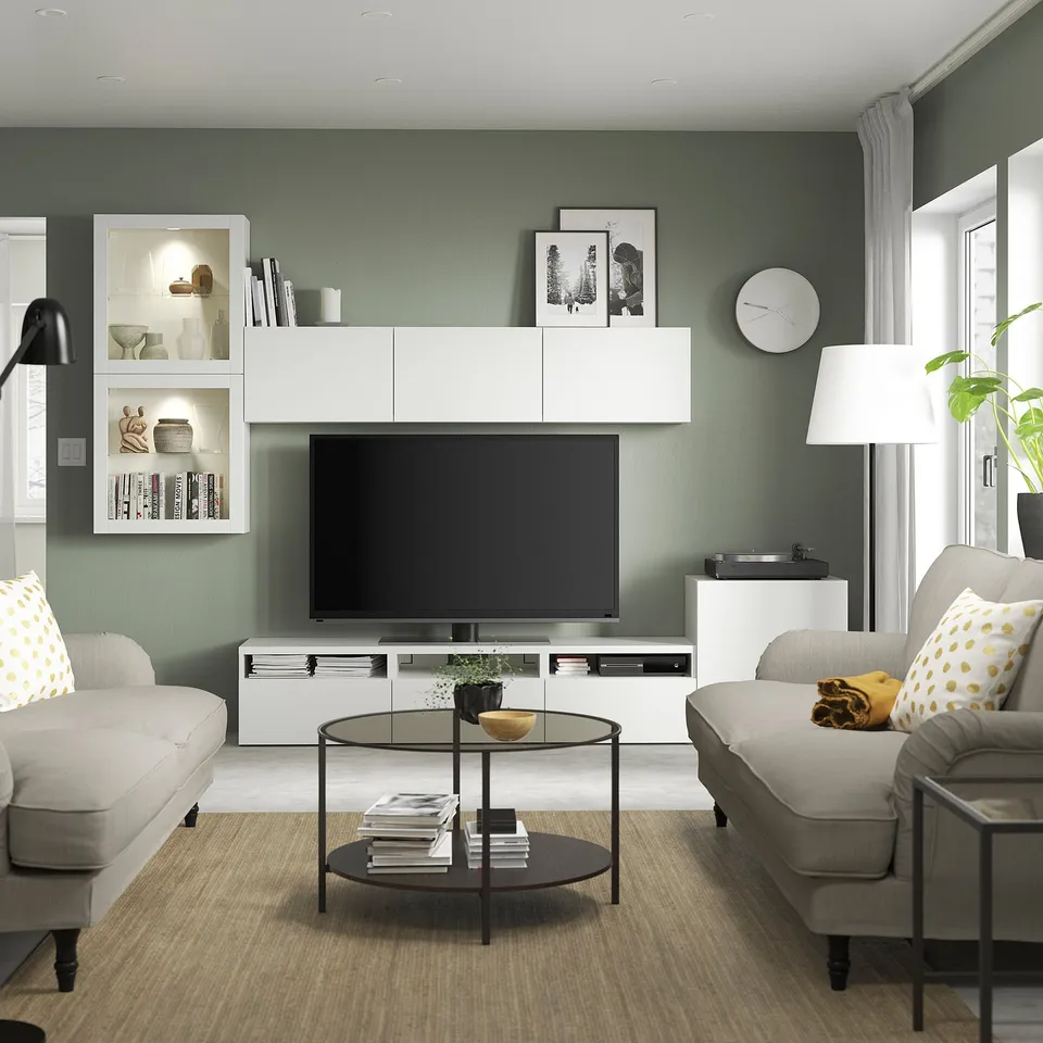 Modern living room with sage walls, BESTÅ tv unit, grey sofas, glass table.