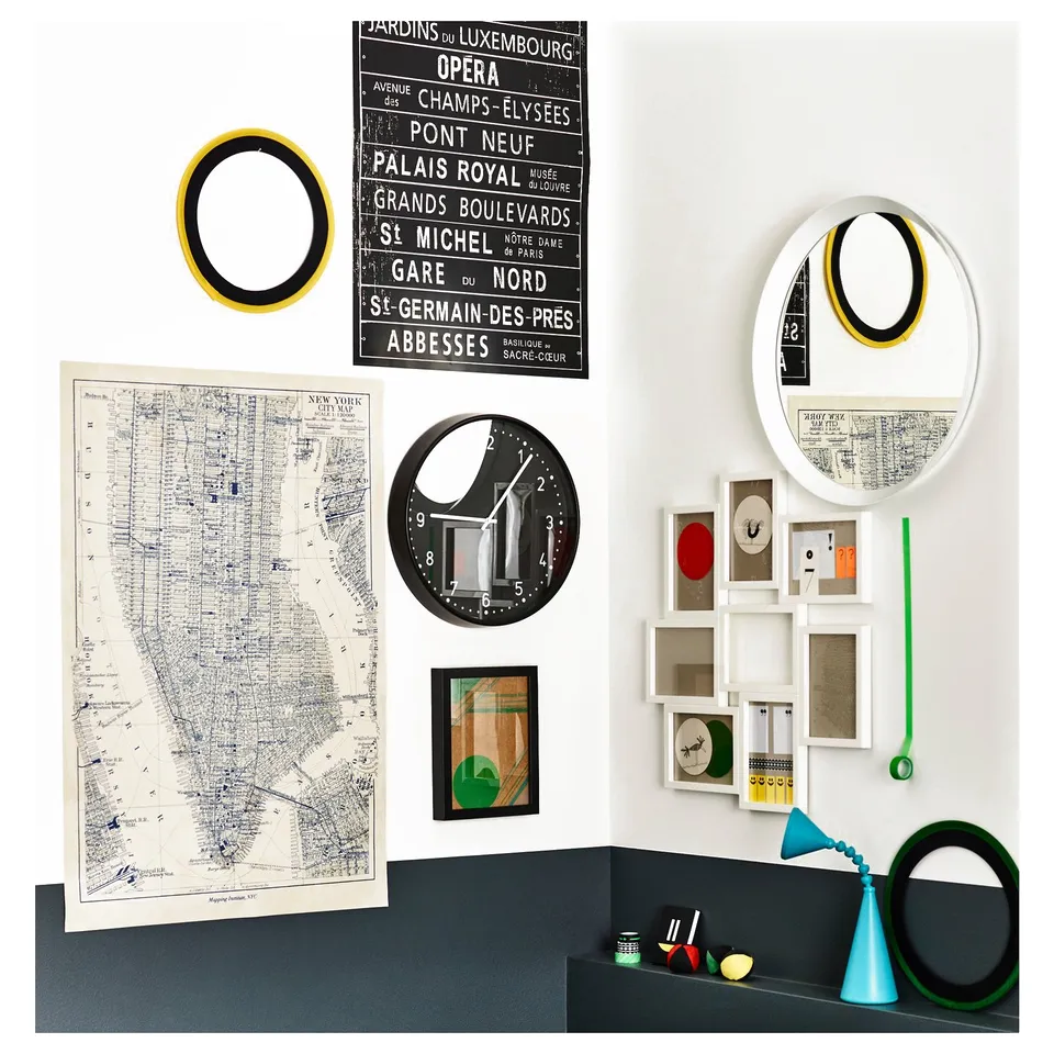 Wall display with various framed items, maps, and mirrors in black, white, green, and yellow, featuring a mix of geometric and artistic designs.