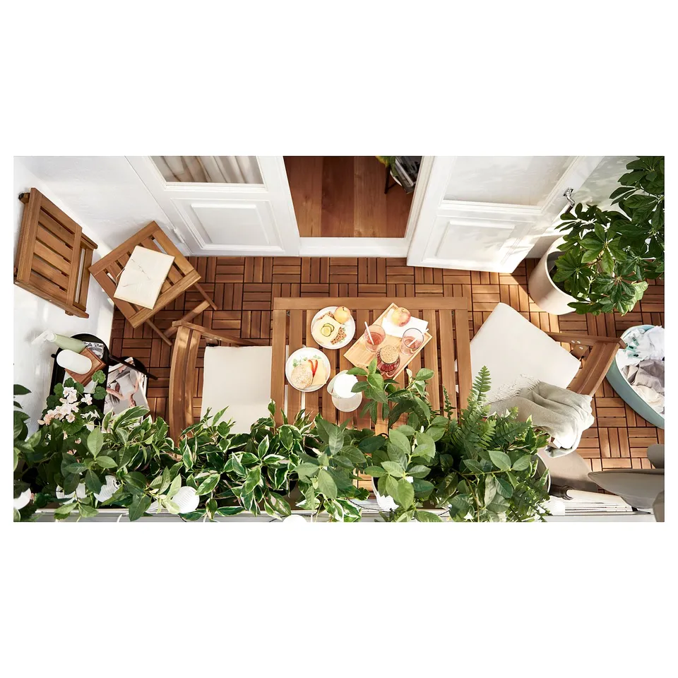 Birds-eye view of a cosy balcony: wooden patio furniture set, food, plants.