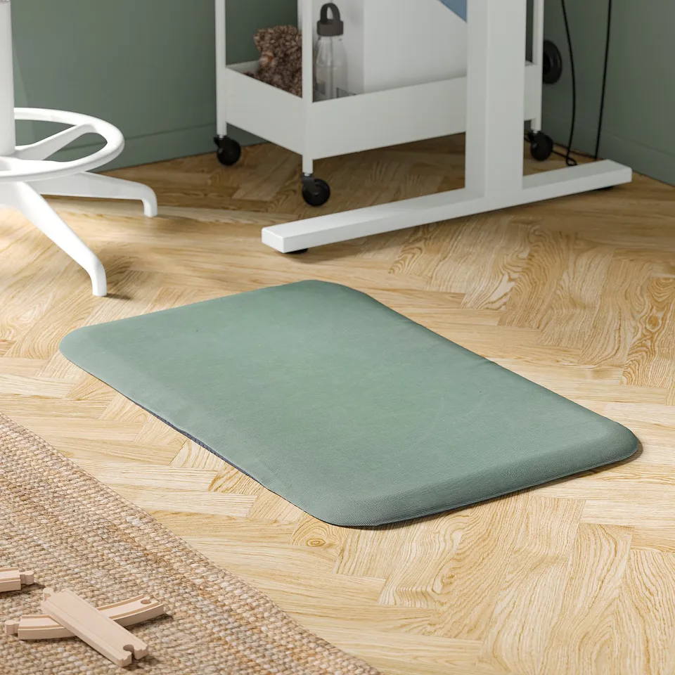 Green MITTZON mat on wooden floor with standing desk and chair.
