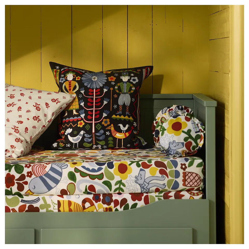 Brightly patterned cushions: folk art designs in vivid colours on bed.
