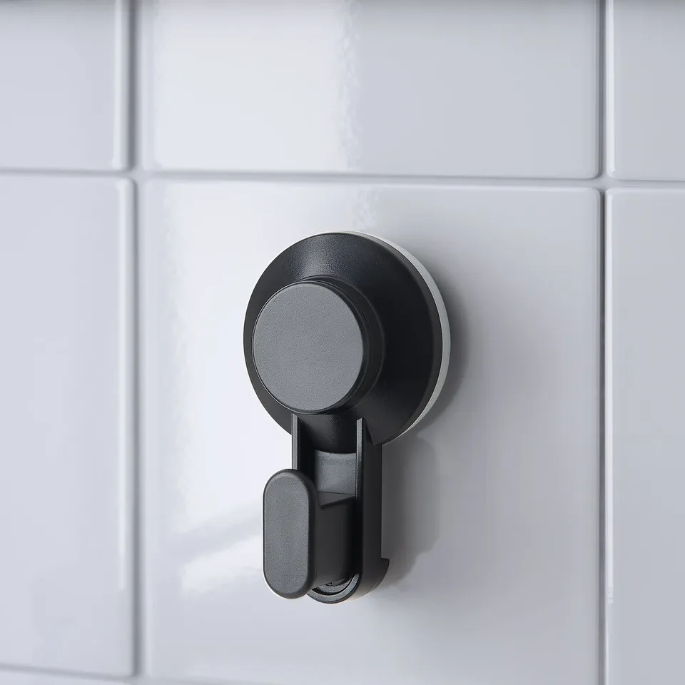 Black suction cup hook on white tiles, securely hanging items up to 3 kg.