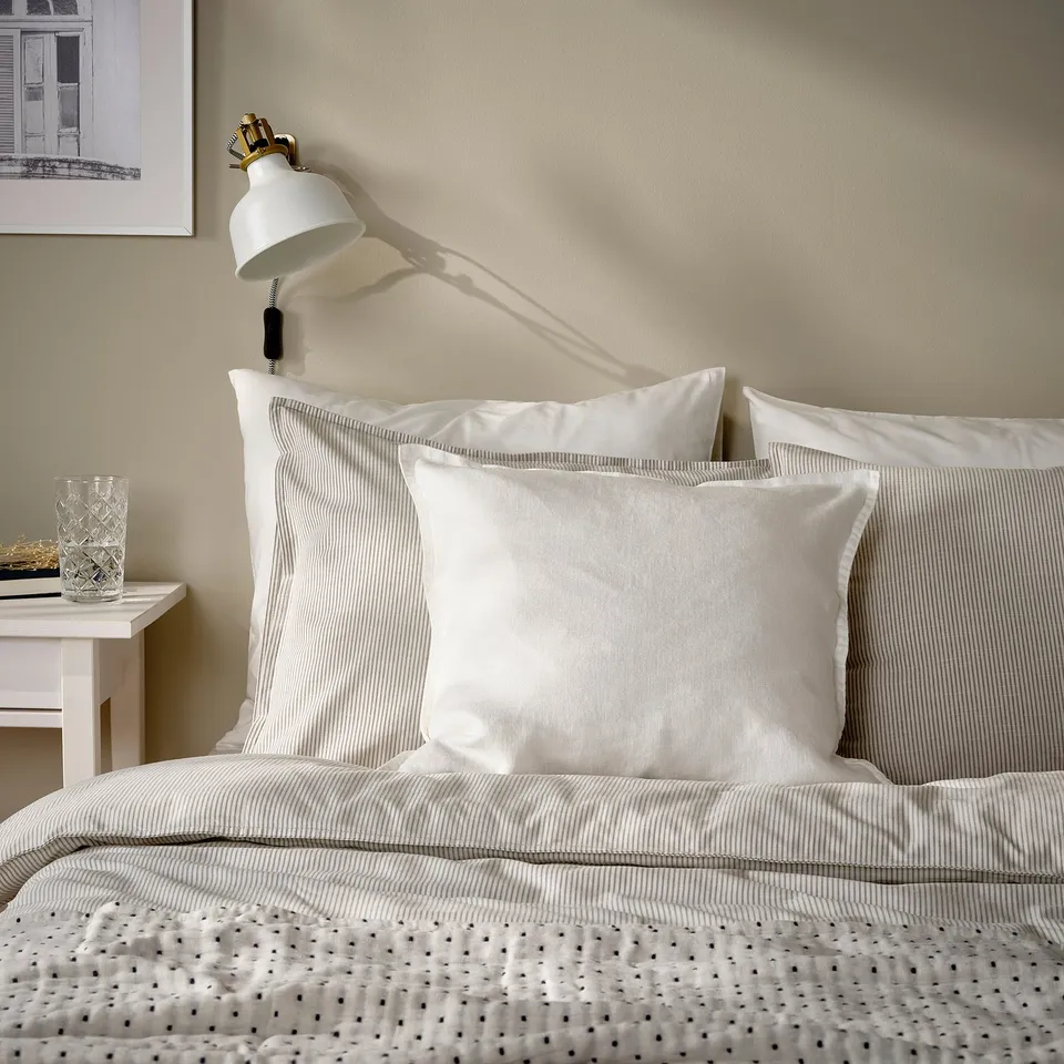 White linen cushion cover on bed, square, simple design.