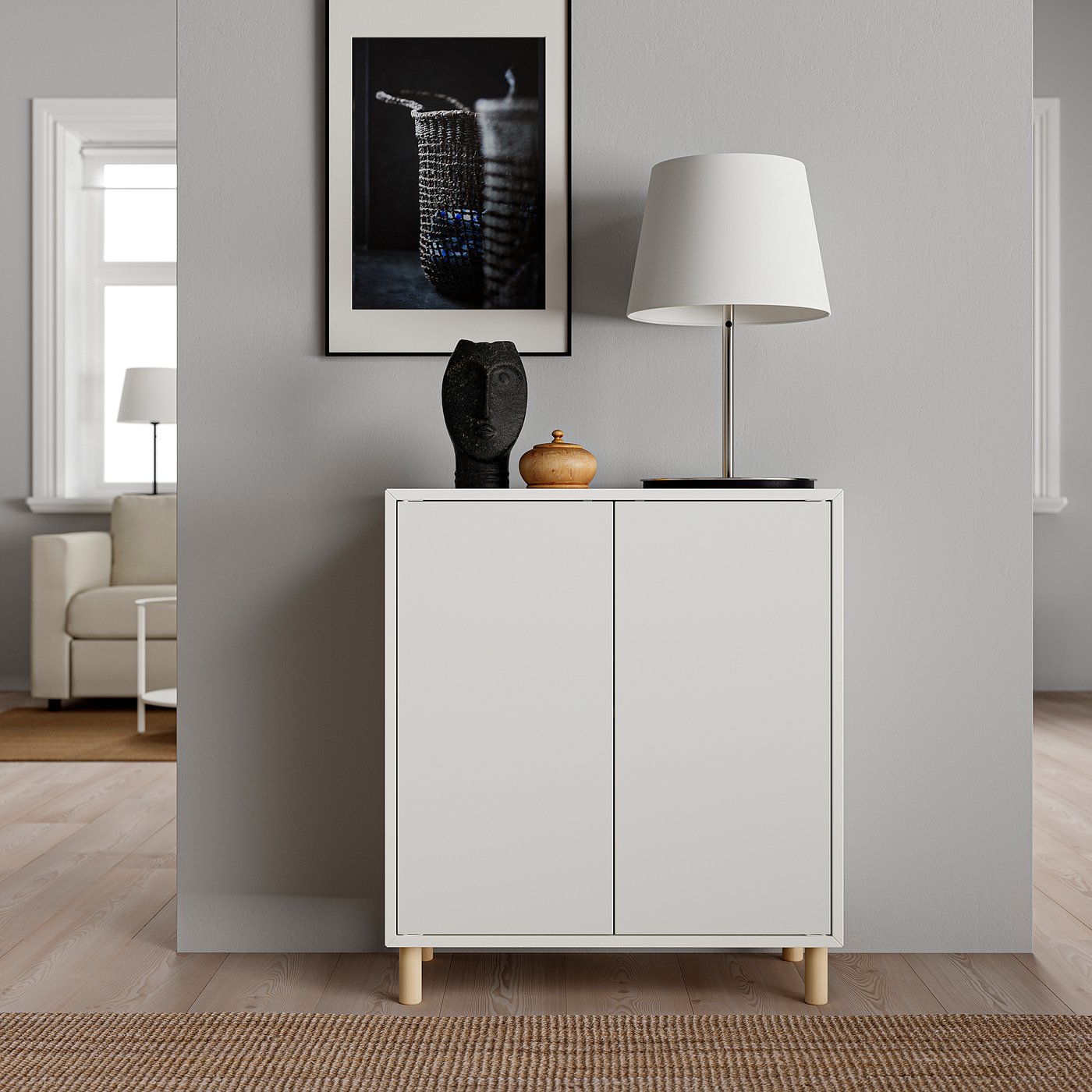 Modern living room EKET white cabinet with wooden legs, table lamp, sculpture, and framed art.