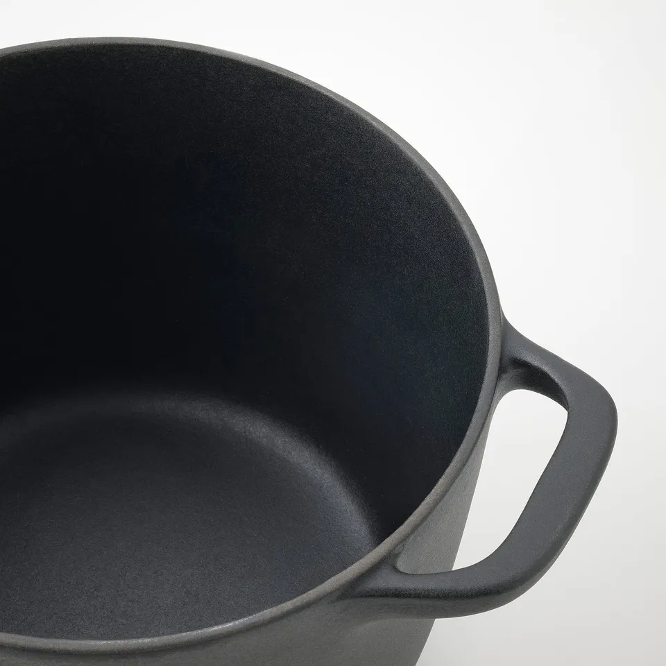 Black enamel cookware close-up showing smooth, even interior surface and sturdy handles.