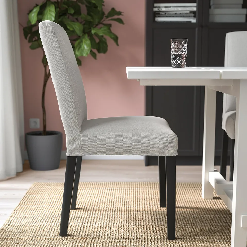 Grey fabric chair with black legs near table on rug.