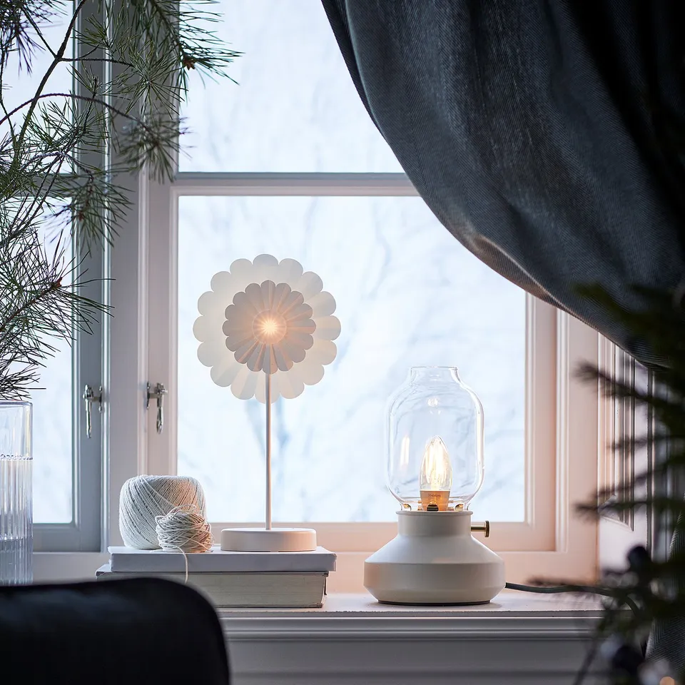 Cosy window sill with lamp, books, pine branches.