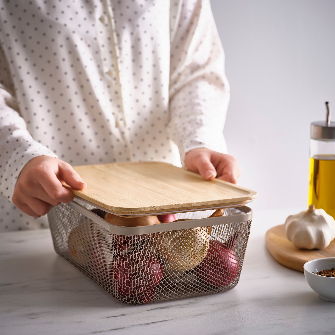 A person opens an IKEA 365+ mesh fruit basket on the kitchen counter.