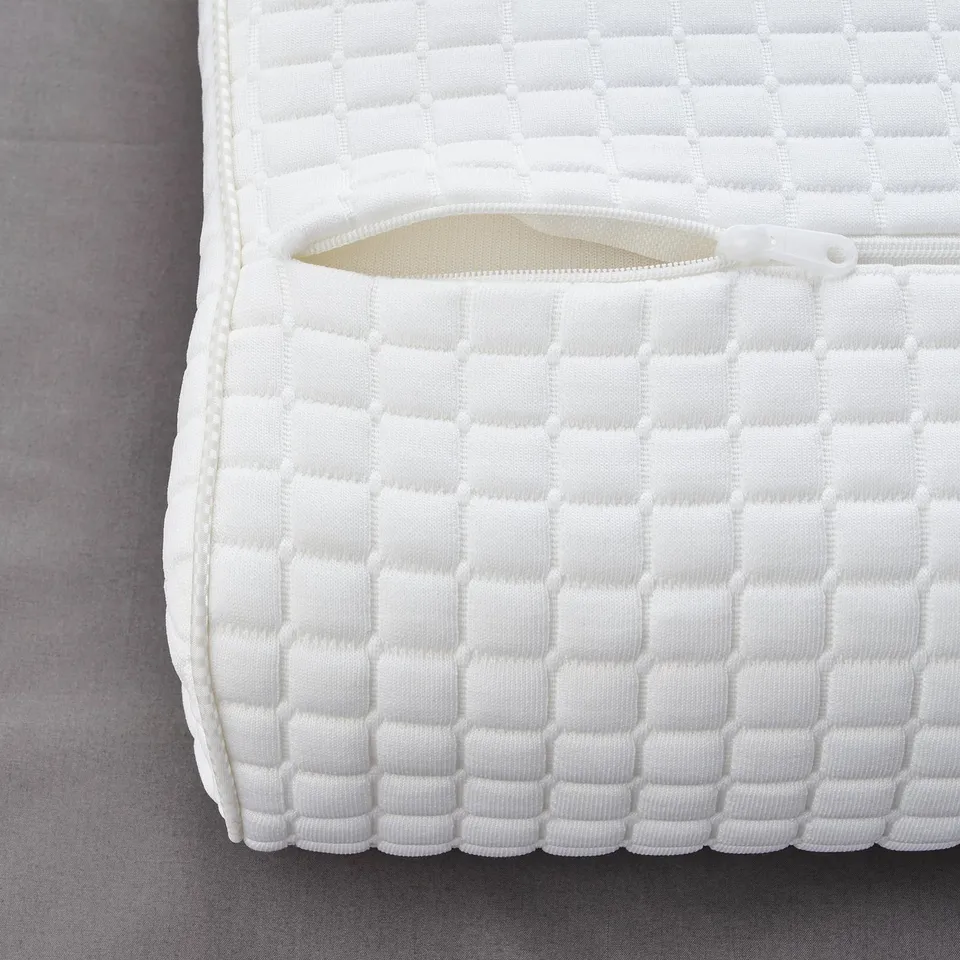 Close-up of plush pillow: textured white surface with zip pocket, quality evident.