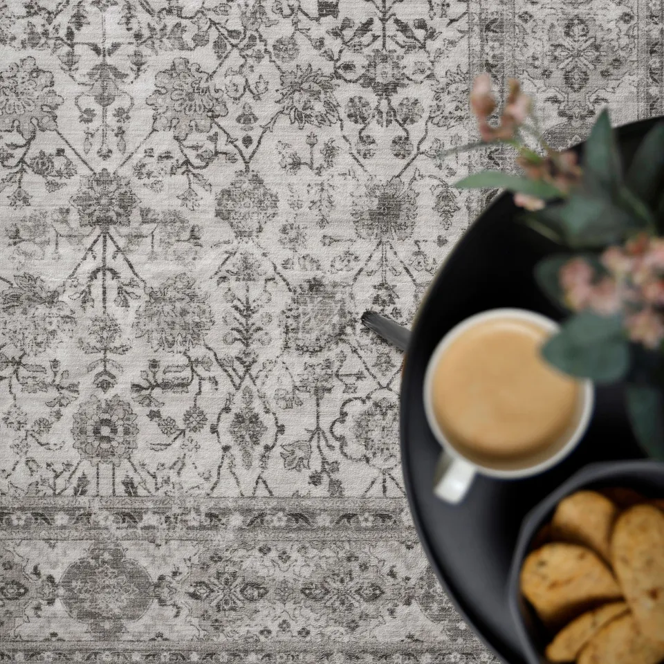 Patterned tablecloth with a cup of drink, cookies, and plant.