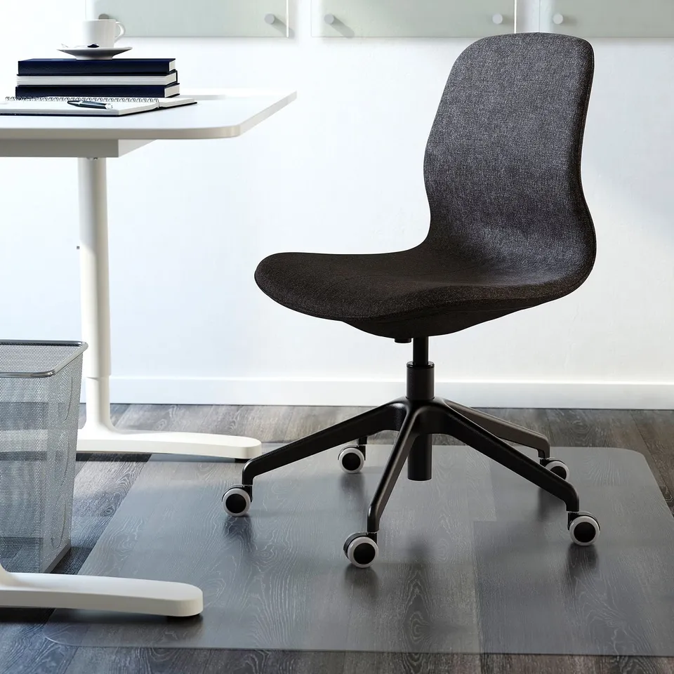 Dark grey office chair with adjustable height and tilt mechanism on clear mat under desk.