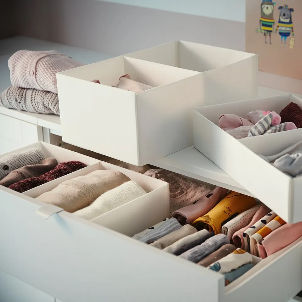White SMÅSTAD kids dresser with four open drawers, showing organised baby clothes in white and beige colours.