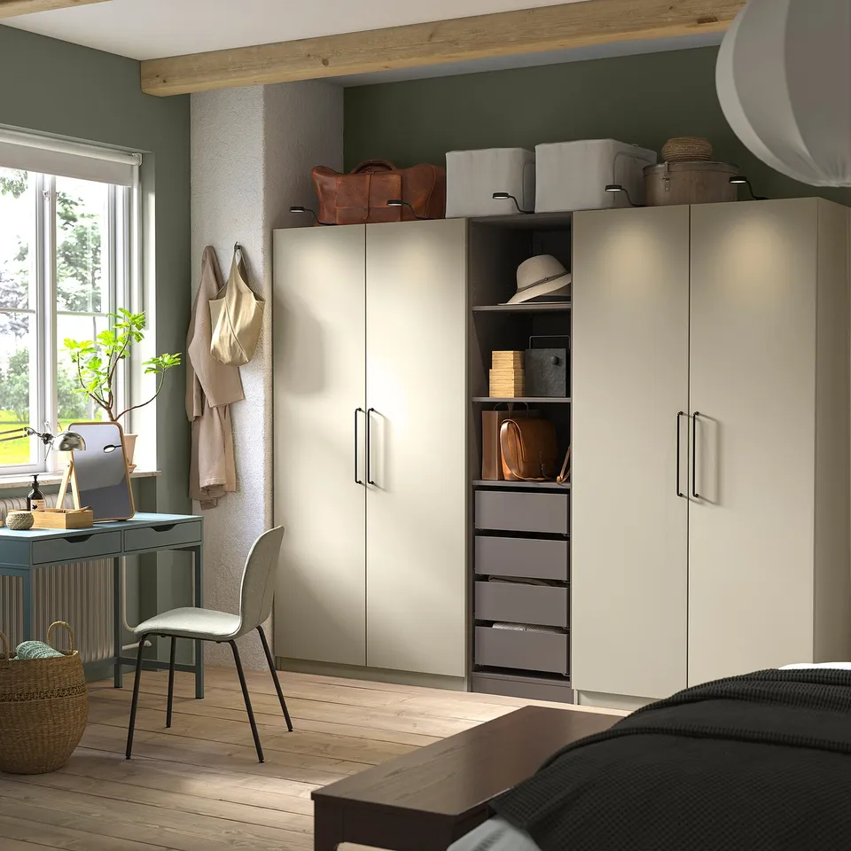 Modern bedroom with PAX wardrobes, desk, and plant.