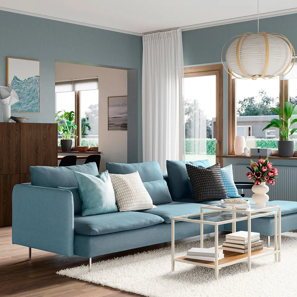 Modern living room with SÖDERHAMN light blue sofa, wooden cabinet, glass coffee table, and large windows.
