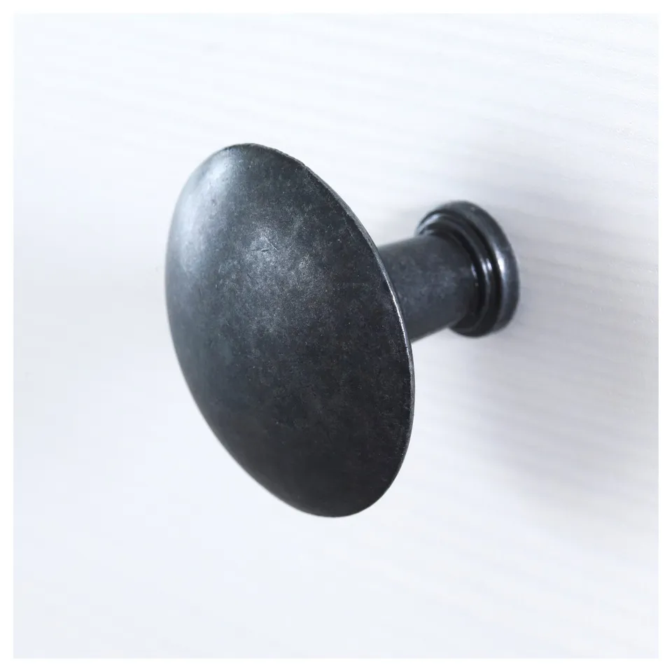 Dark metal wall hook, round design, smooth finish, mounted on light wall.
