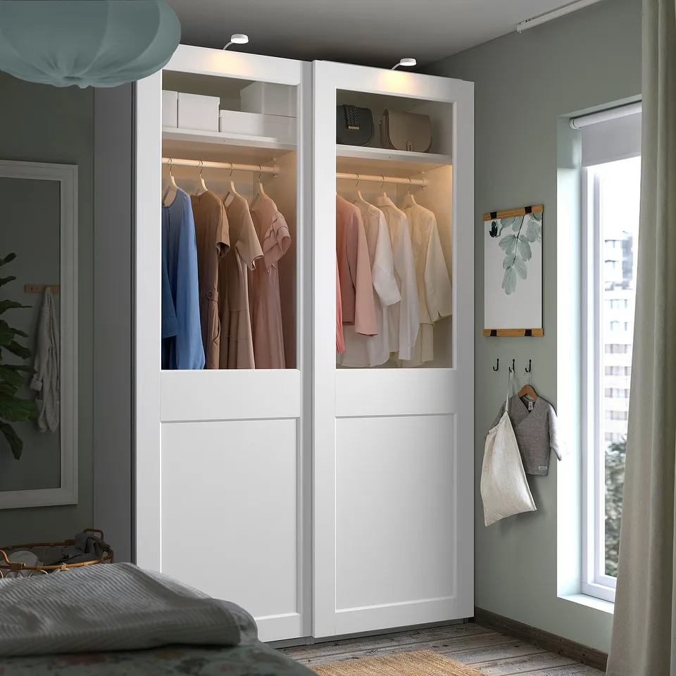 Modern bedroom with large PAX wardrobe, glass doors, and neat clothes.