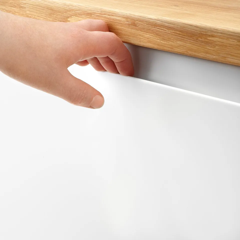 A hand pulls a white drawer from a wooden cabinet, showcasing its smooth, matte surface and integrated handle design.