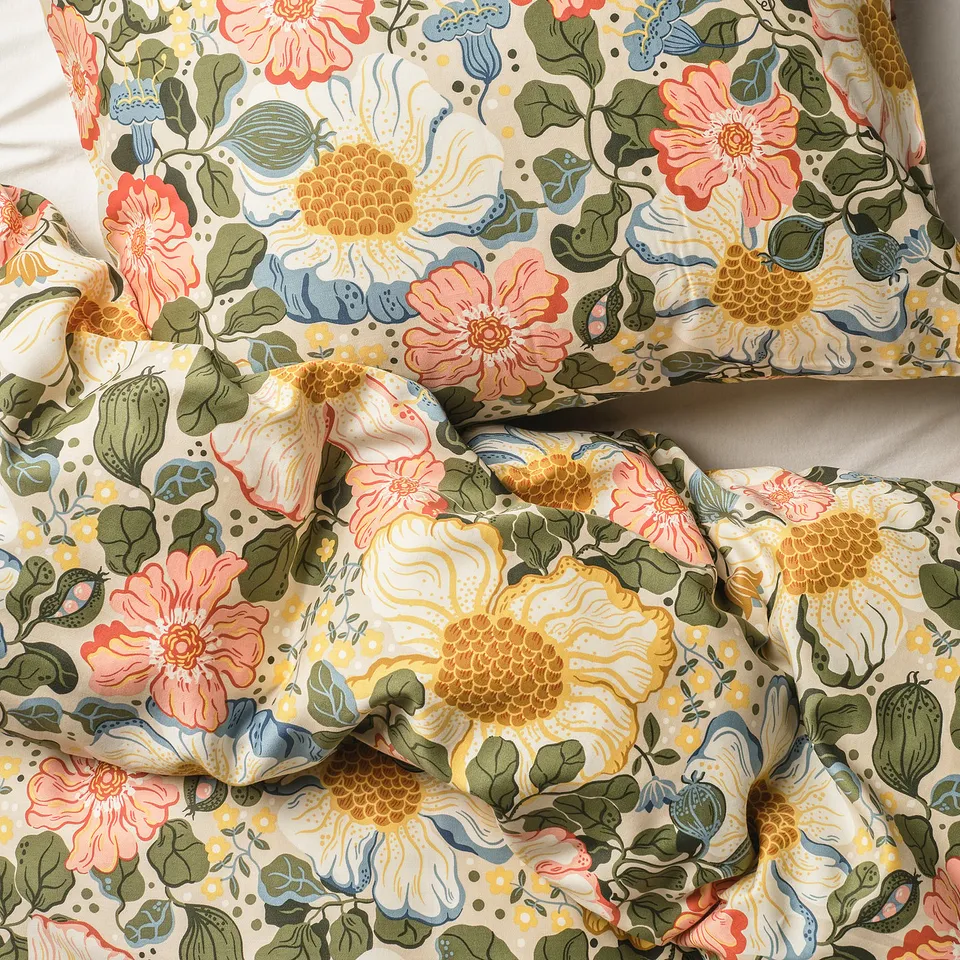 Floral bedding with intricate pink, yellow, and green flowers on beige fabric, showcasing silky texture and high-quality design.
