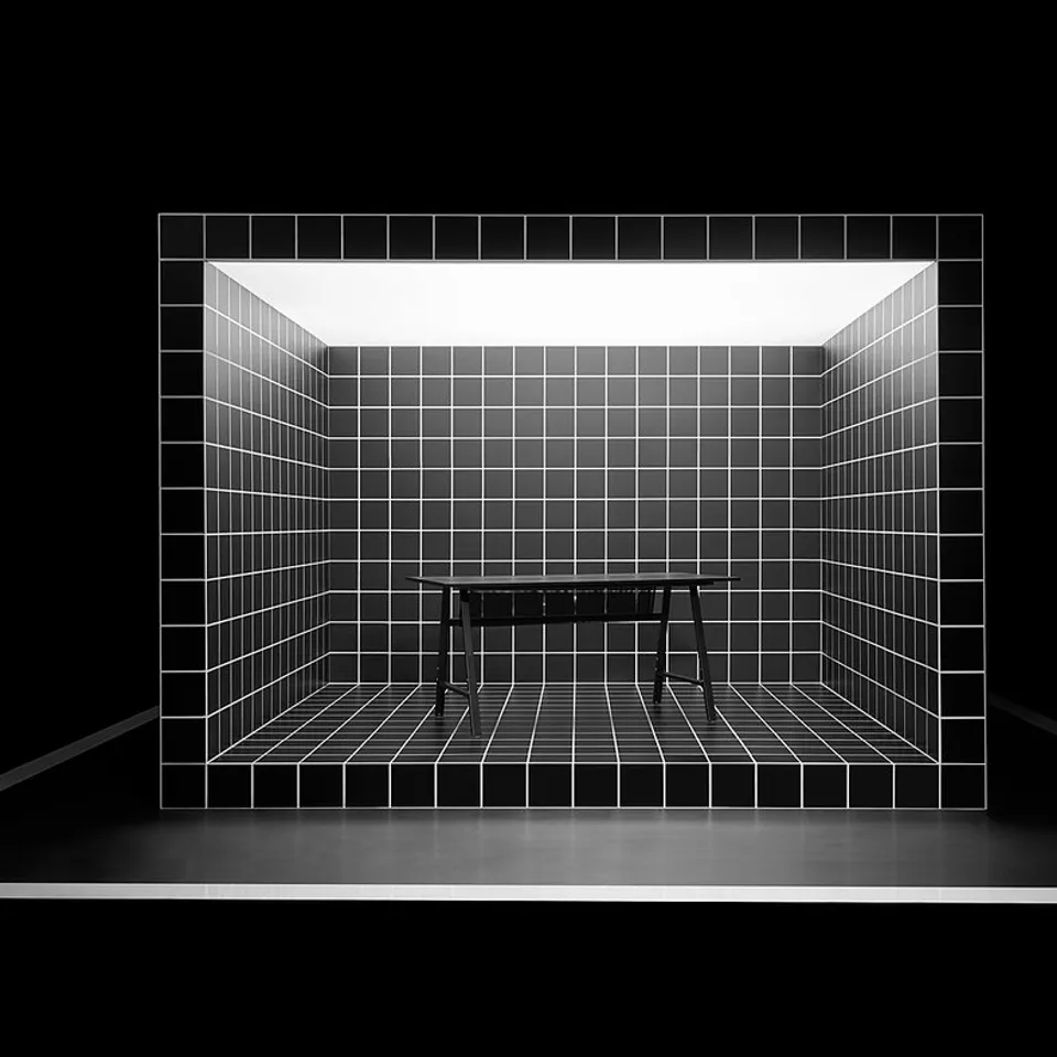 Black and white a large grid-like gaming setup with a black desk on a grey floor.