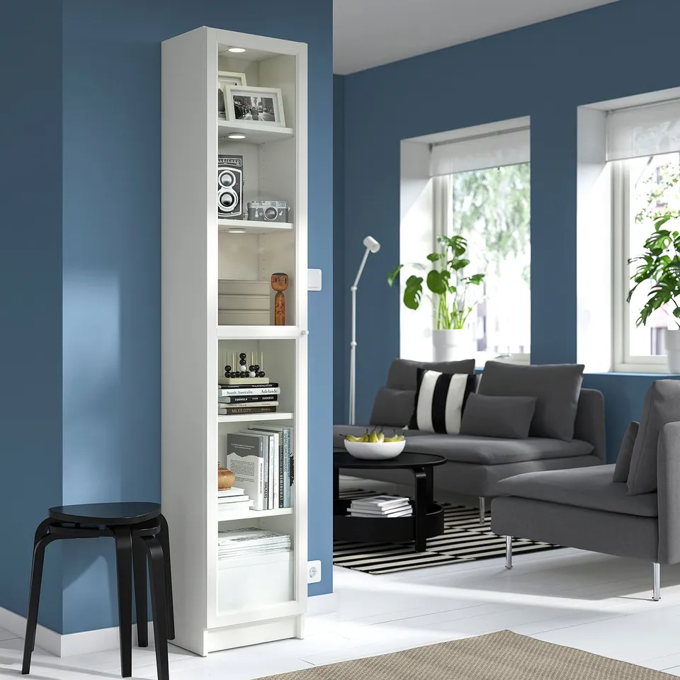 White BILLY bookcase with books & decor against blue wall.