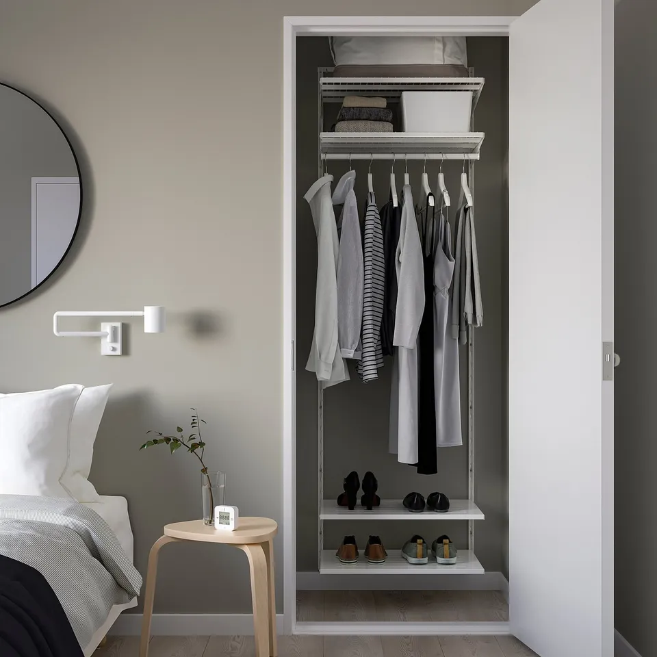 BOAXEL wall storage: white, with shelves and hanging rods for clothes, reaching near ceiling.