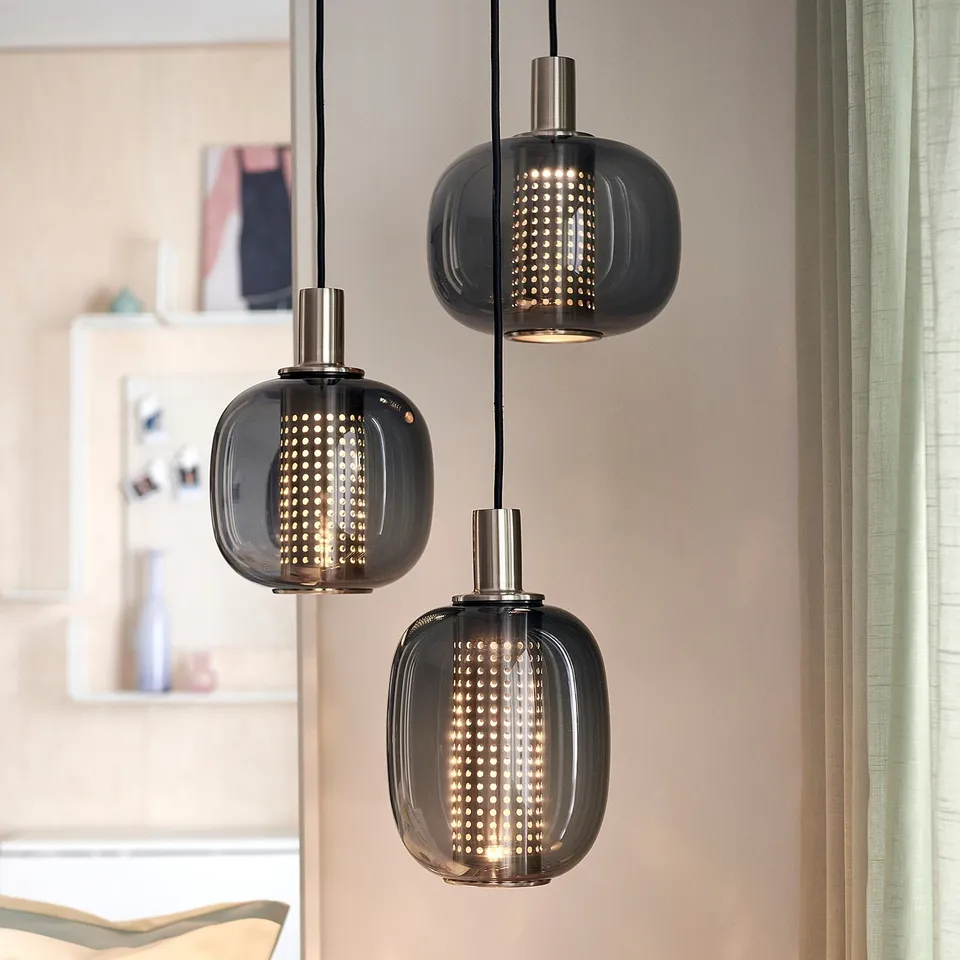 Three smoky glass pendant lamps with perforated shades, brass finish.