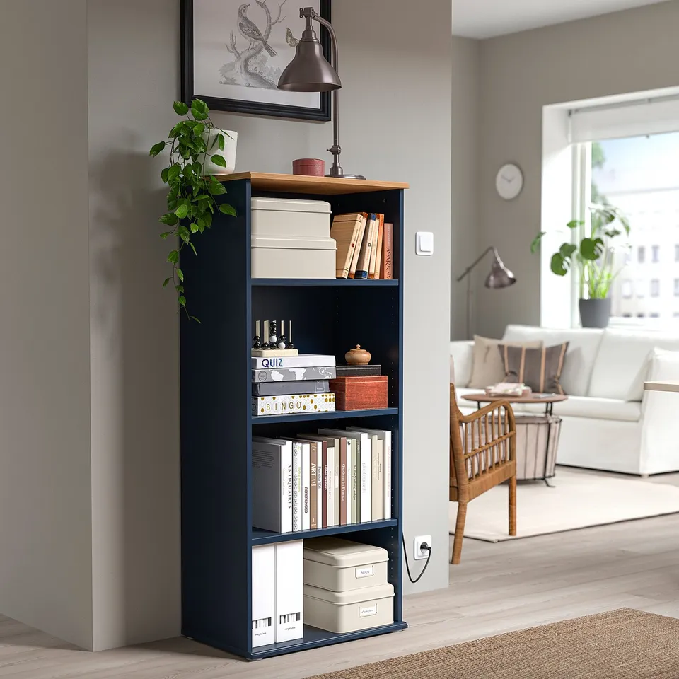 PLOGFÅRA: dark blue, tall, 4-shelf bookcase with storage boxes, plant, lamp, books, and wooden floor.