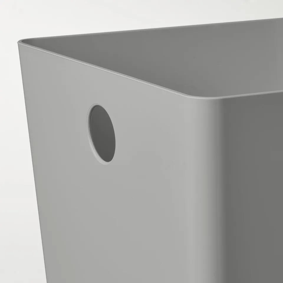 Close-up of sleek, modern storage box. Oval handle on smooth, light grey plastic surface.